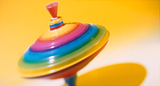 a colorful, spinning top on a solid yellow background. the spinning top symbolizes the autistic urge to spin around.